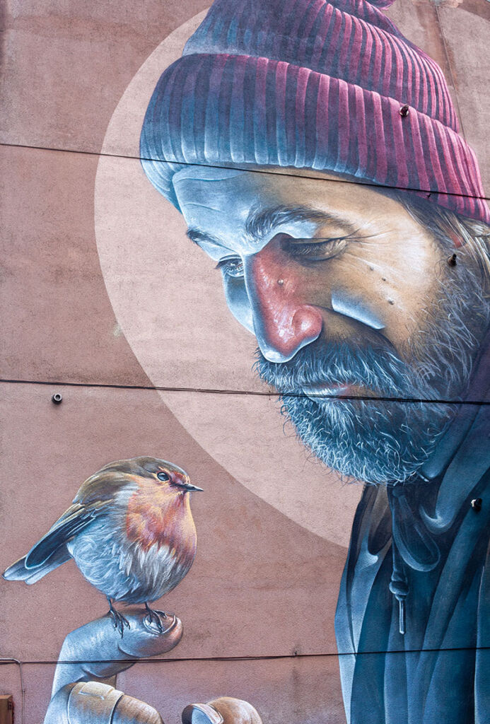 large scale mural of man with bird on the side of a building