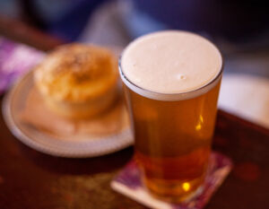 pint of beer next to a meat pie